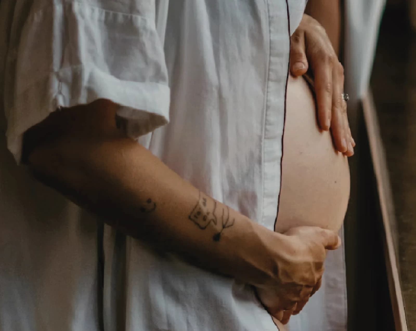 Une femme enceinte en chemise blanche tenant son ventre